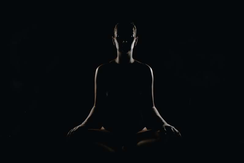 Two diverse adults sitting comfortably on floor cushions, eyes closed, smiling softly — beginner meditation setting